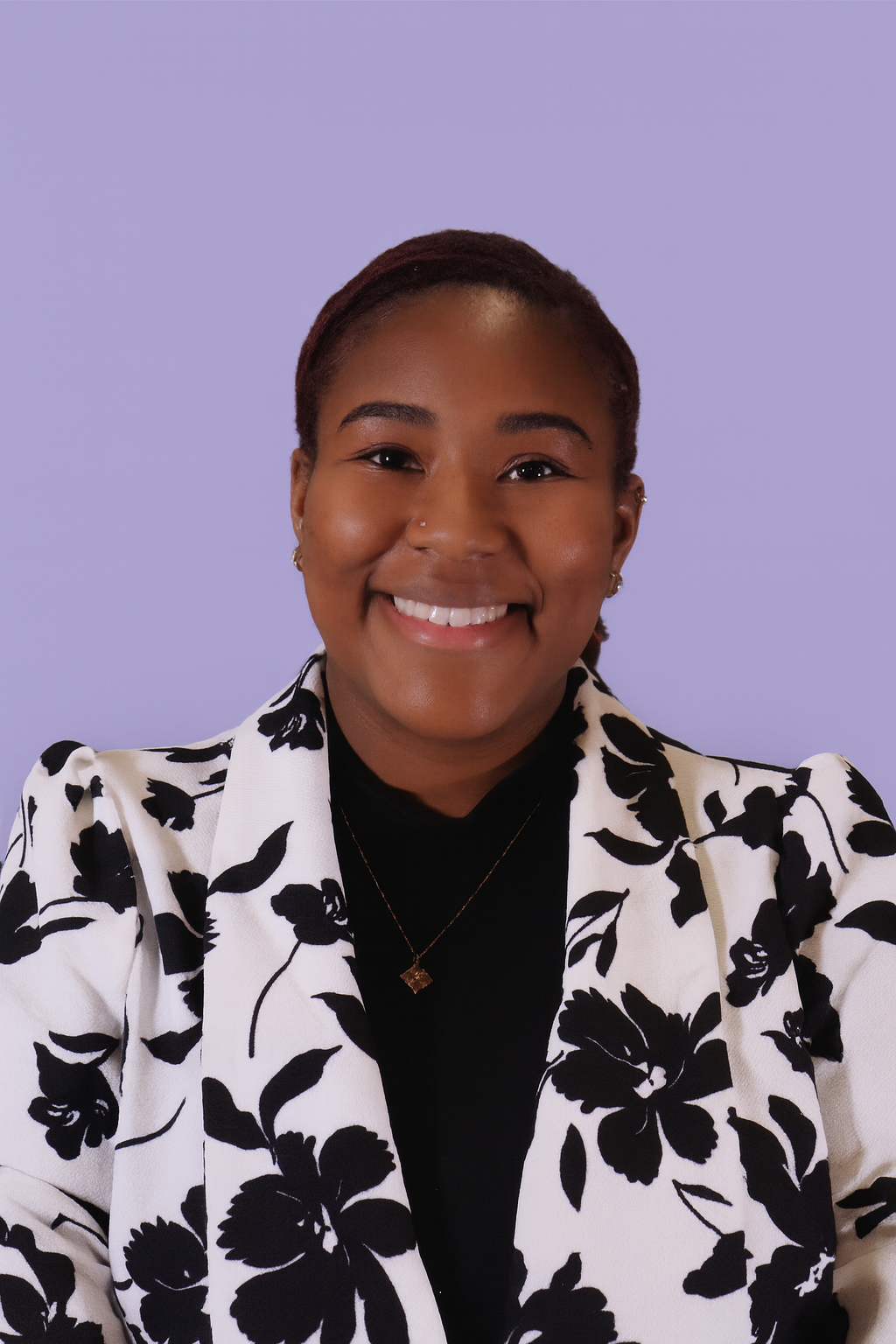 Thomes Buchanan, licensed therapist and owner of She Talks Therapy, smiling against a lavender background